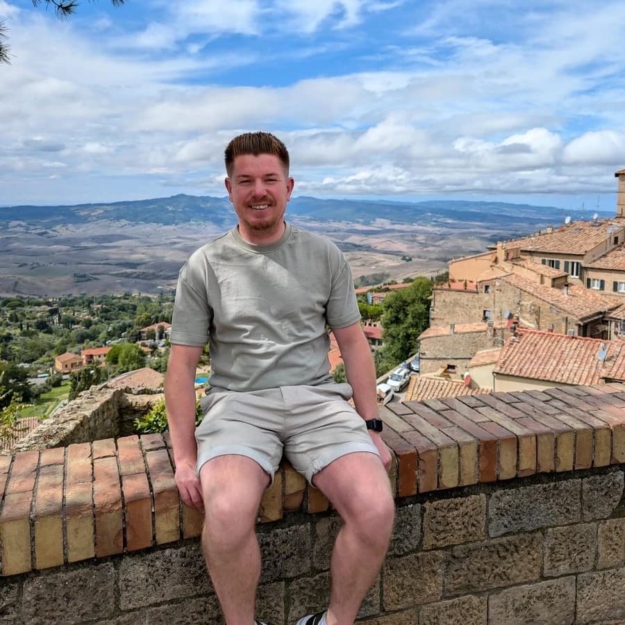 Steffan sat on a wall overlooking Volterra, Italy